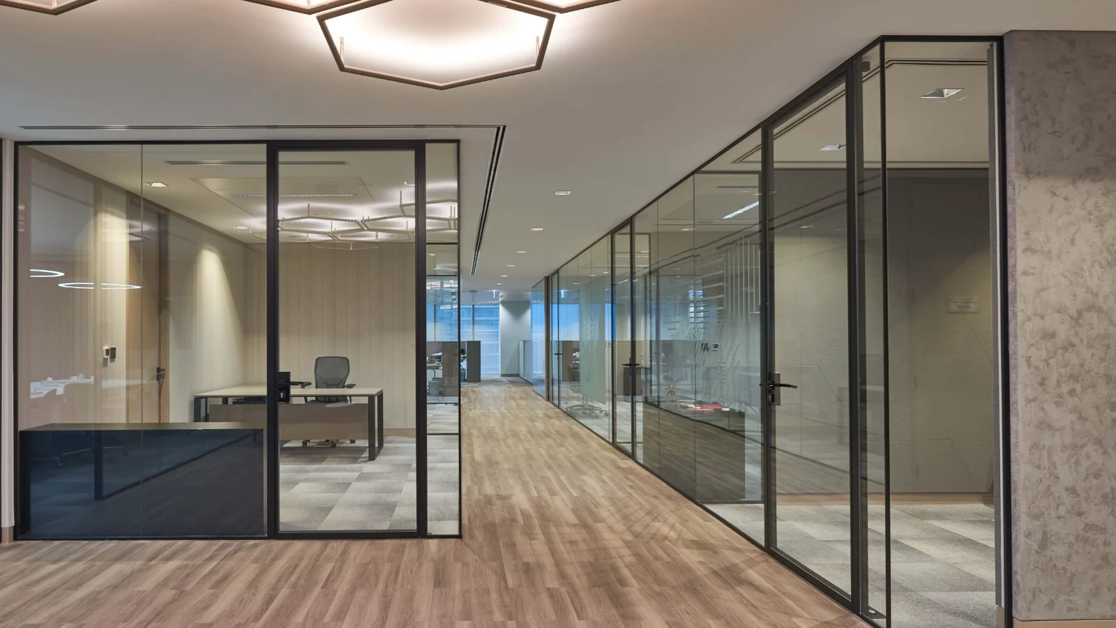 Office corridor with glass-partitioned meeting rooms and glass doors on both sides